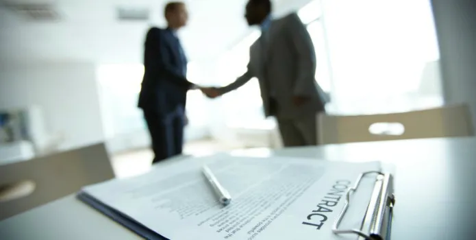 Two business people shaking hands over a signed contract