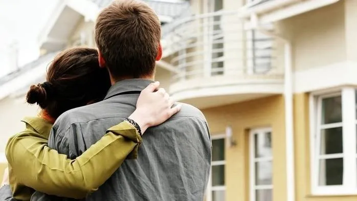 A couple standing in front of a house