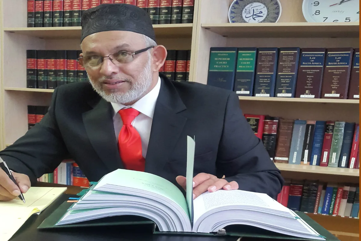 Ismail Mohamed at his desk in front of shelves of law reports