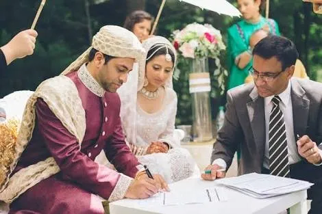 A bride and groom at their nikah while the marriage contract is signed
